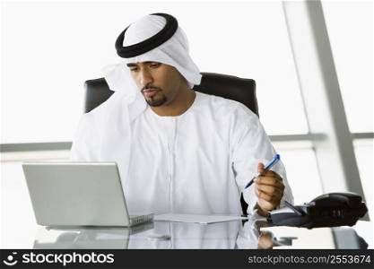 Businessman in office with laptop working (high key/selective focus)