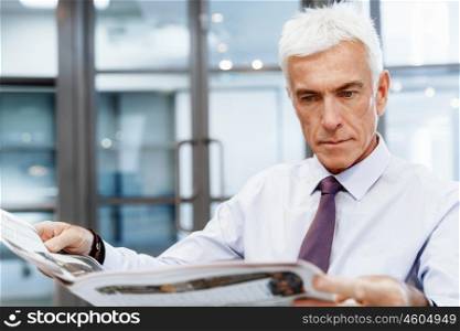Businessman in office with newspaper. Learning the news