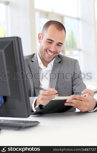 Businessman in office writing on agenda