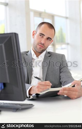 Businessman in office writing on agenda