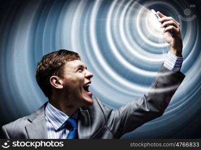 Businessman in rage. Aggressive businessman screaming fiercely in mobile phone
