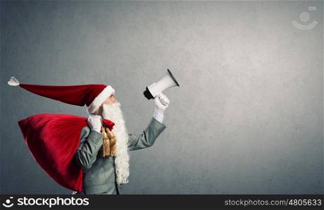 Businessman in Santa costume shouting in megaphone