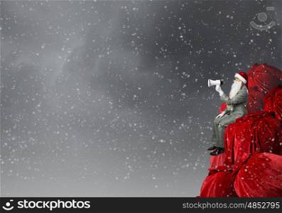 Businessman in Santa costume shouting in megaphone