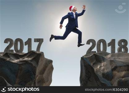 Businessman in santa hat jumping from 2017 to 2018. The businessman in santa hat jumping from 2017 to 2018