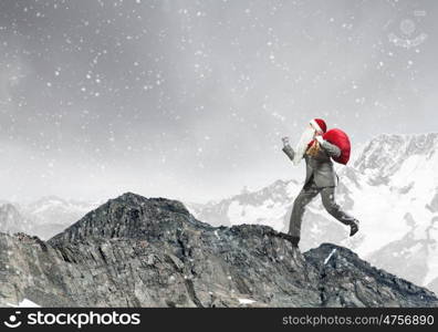 Businessman in Santa hat running with bag on back