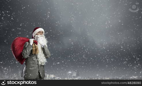 Businessman in Santa hat with red gift bag behind back