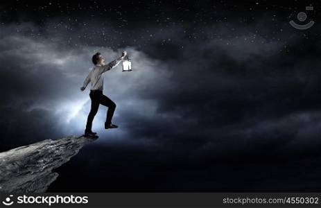 Businessman in search in darkness. Young businessman walking with lantern in darkness