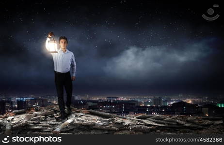 Businessman in search in darkness. Young businessman walking with lantern in darkness