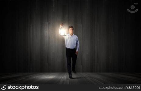 Businessman in search in darkness. Young businessman walking with lantern in darkness