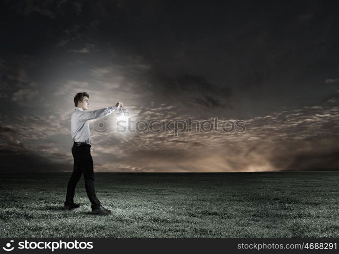 Businessman in search in darkness. Young businessman walking with lantern in darkness