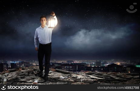 Businessman in search in darkness. Young businessman walking with lantern in darkness