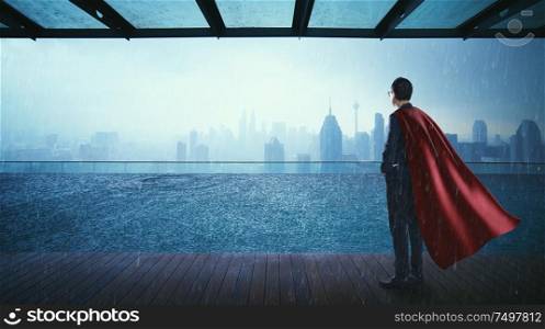 Businessman in suit and cape hero stand at swimming pool on roof top with beautiful city skyline view,rainingday .
