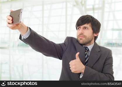 businessman in suit and tie taking selfie photo with mobile phone camera posing happy and successful at the office. taking a selfie