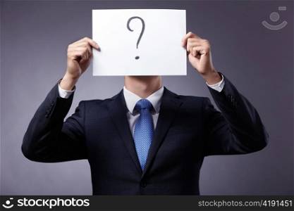 Businessman in suit holding a sign with a question mark