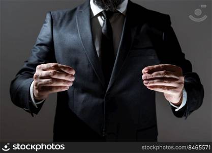 Businessman In Suit Holding Important Informations Between Hands.. Businessman Holding Important Message Between Hands. Man In Suit Presenting Crutial Informations Among Palms. Executive Showing Recent Announcements. New Ideas Displayed.