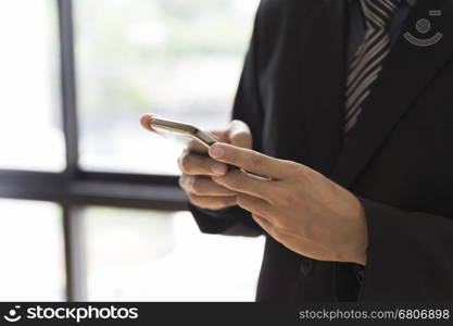 businessman in suit holding smartphone beside window