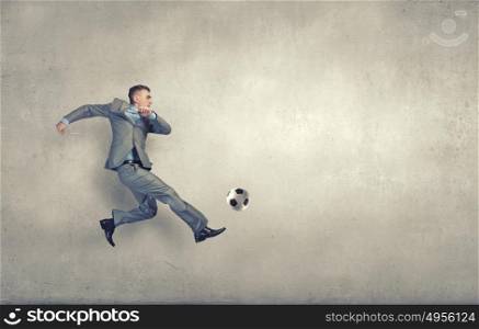 Businessman in suit jumping to hit soccer ball. Hit your goal