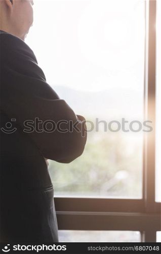businessman in suit looking out through office window