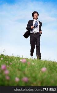 Businessman in suit running on the meadow