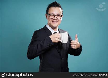 Businessman in suit smile and enjoy cup of coffee with thumb up gesture.