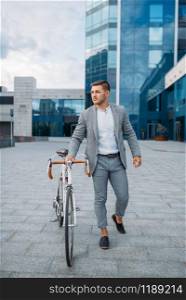 Businessman in suit with briefcase and bicycle in downtown. Business person riding on eco transport on city street. Businessman with briefcase and bicycle in downtown
