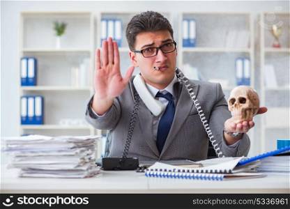 Businessman in the office smoking holding human skull