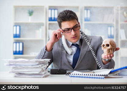 Businessman in the office smoking holding human skull