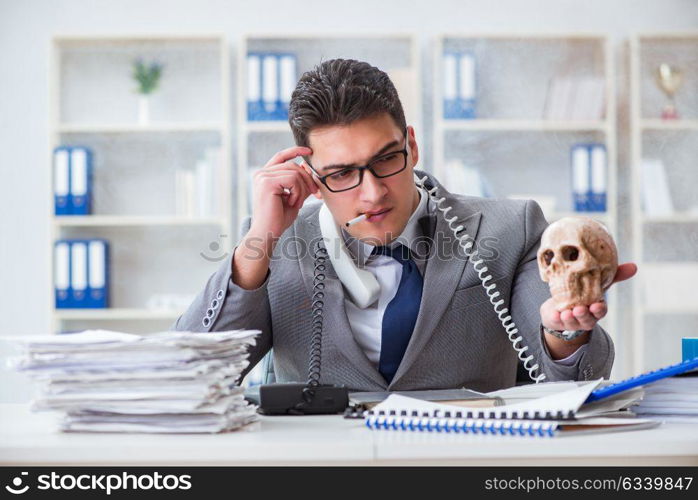 Businessman in the office smoking holding human skull