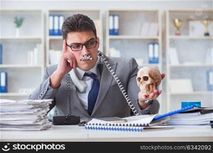 Businessman in the office smoking holding human skull