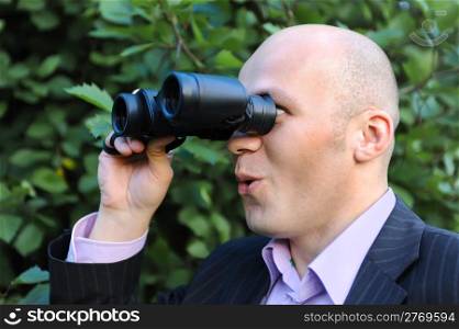 Businessman in the park looking through binoculars