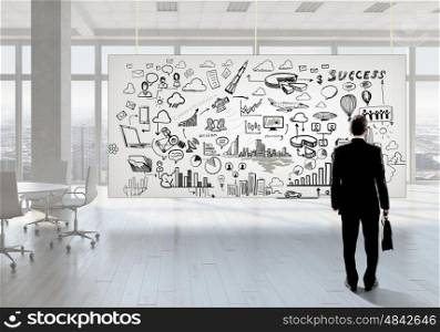 Businessman in top level office. Back view of elegant businessman against banner with business strategy plan
