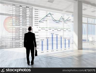 Businessman in top level office. Back view of elegant businessman against modern ofiice window