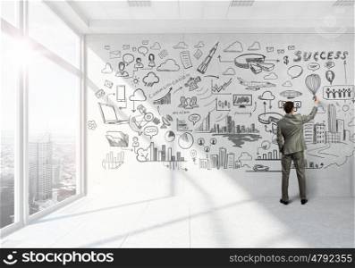 Businessman in top level office. Back view of elegant businessman drawing business strategy plan on wall