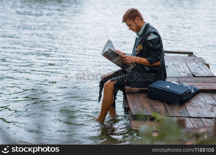Businessman in torn suit reading newspaper on desert island. Business risk, collapse or bankruptcy concept