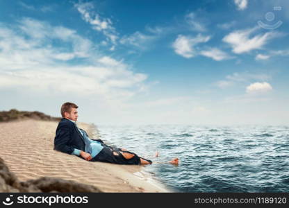 Businessman in torn suit resting on the beach on lost island. Business risk, collapse or bankruptcy concept