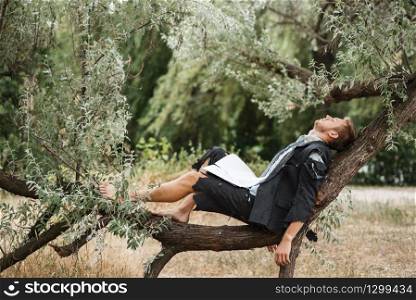 Businessman in torn suit resting on the tree on desert island. Business risk, collapse or bankruptcy concept