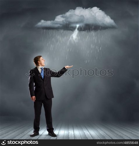 Businessman in trouble. Young businessman catching raindrops with palm. Failure concept