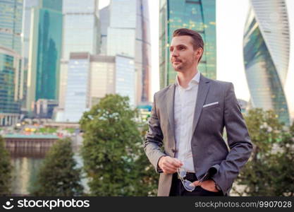 Businessman in urban city with skyscrapers buildings in the background.. Businessman looking on copy space while standing against glass skyscraper