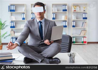 Businessman in virtual reality VR glasses meditating at desk top. The businessman in virtual reality vr glasses meditating at desk top