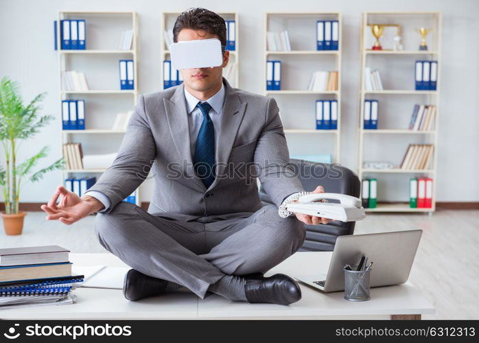 Businessman in virtual reality VR glasses meditating at desk top. The businessman in virtual reality vr glasses meditating at desk top