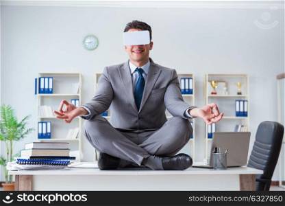 Businessman in virtual reality VR glasses meditating at desk top. The businessman in virtual reality vr glasses meditating at desk top