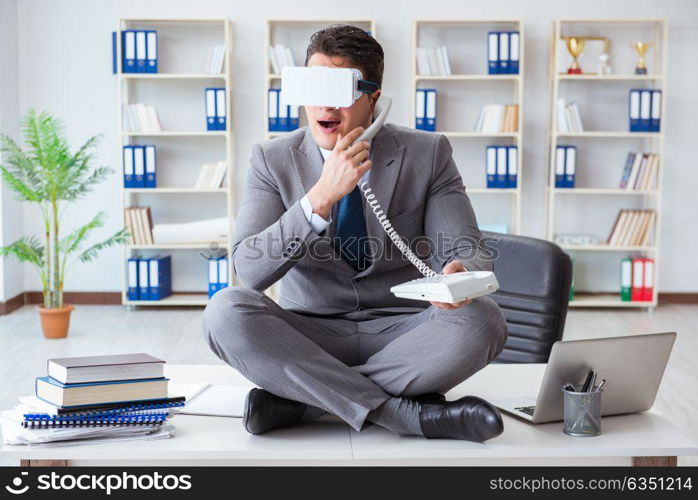 Businessman in virtual reality VR glasses meditating at desk top