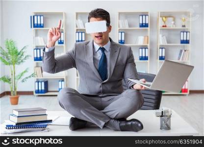 Businessman in virtual reality VR glasses meditating at desk top