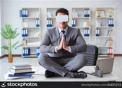Businessman in virtual reality VR glasses meditating at desk top
