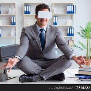 Businessman in virtual reality VR glasses meditating at desk top. The businessman in virtual reality vr glasses meditating at desk