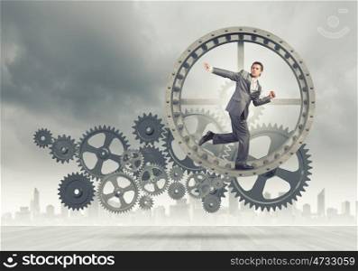 Businessman in wheel. Young businessman in suit running in hamster wheel