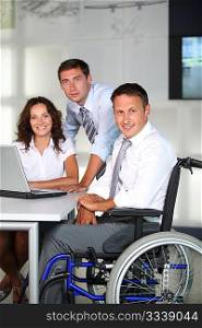 Businessman in wheelchair working in the office with colleagues