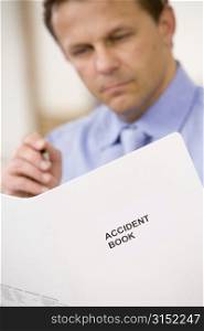 Businessman indoors looking at Accident Book