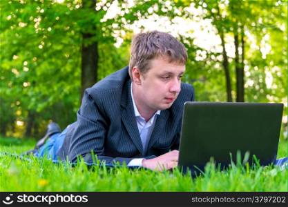 businessman intently working on a laptop on the grass