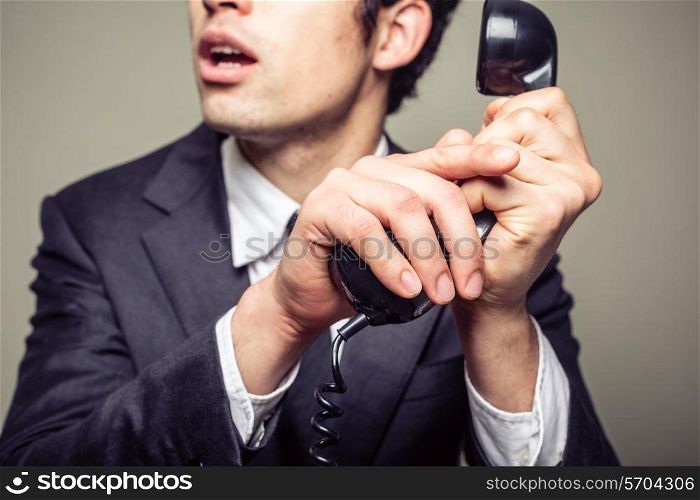 Businessman is covering the phone to speak in private to someone in the room